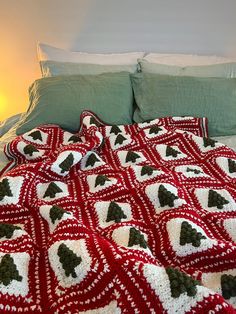 a crocheted christmas blanket on a bed with green pillows and blankets around it