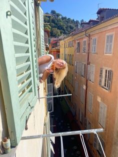 a woman standing on top of a balcony next to buildings