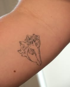 a woman's arm with a small tattoo of a bear on the back of it