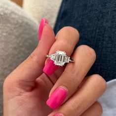 a woman's hand with pink nail polish and an engagement ring on her finger