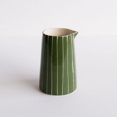 a green and white striped vase sitting on top of a table