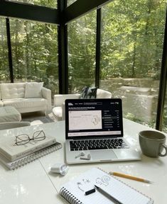 an open laptop computer sitting on top of a white table next to a coffee cup