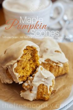 two pumpkin scones with white frosting on a plate next to a cup of coffee