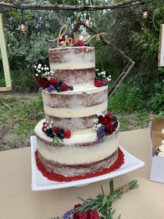 a three tiered cake sitting on top of a white plate next to flowers and greenery