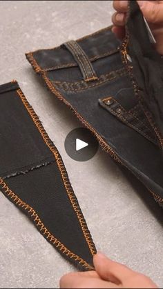 someone is cutting out the bottom part of a pair of black jeans with gold stitching