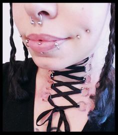 a close up of a person with piercings on her nose and neck chain attached to their chest