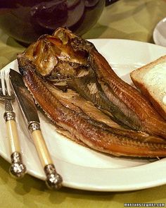 a white plate topped with meat and vegetables covered in gravy next to a pickle