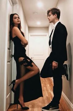 a man in a suit standing next to a woman in a black dress and high heels