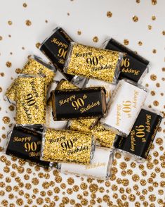 gold and black birthday candy wrappers with the number 90 printed on them, surrounded by golden confetti