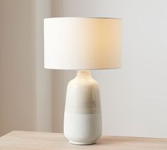 a white lamp sitting on top of a wooden table