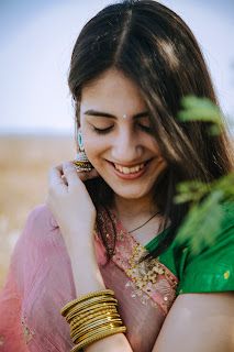 a woman in a green and pink sari smiles as she holds her hand on her shoulder