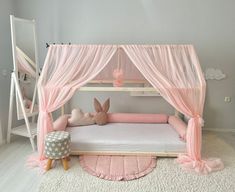 a child's bed with pink drapes and bunny ears on the headboard