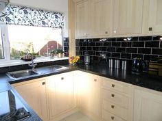 a kitchen with white cabinets and black counter tops next to a window that looks out onto the backyard