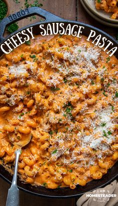 a skillet filled with cheesy sausage pasta on top of a wooden table