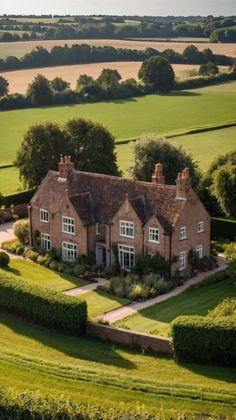 an aerial view of a large house surrounded by lush green fields