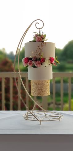 a three tiered cake sitting on top of a white table next to a fence