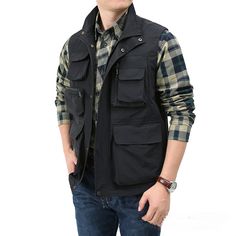 a young man wearing a black vest and plaid shirt is posing for the camera with his hands in his pockets