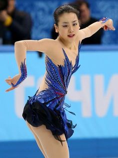 a woman in a blue dress skating on an ice rink