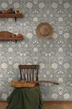 a wooden chair sitting in front of a wall with a hat on top of it