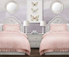 two white beds with pink comforters and pillows in a room decorated with butterflies on the wall