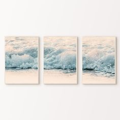 three canvases on the wall with waves crashing in front of them, one is white and