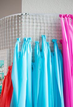 several different colored umbrellas are hanging on a wire rack in front of a white wall