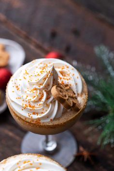 two glasses filled with hot chocolate and topped with whipped cream, sprinkled with cinnamon