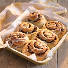 a pan filled with cinnamon rolls on top of a wooden table