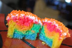 a rainbow cake with white frosting and sprinkles sitting on top of a table