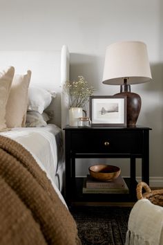 a bedroom with a bed, nightstand and pictures on the side table next to it