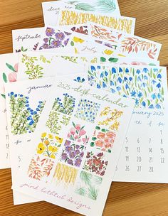 several calendars with flowers on them sitting on a wooden table next to each other