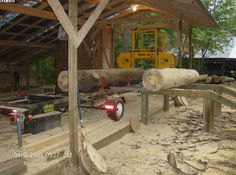 there is a construction site with logs in the foreground and a yellow forklift in the background