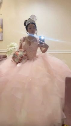 a woman in a pink dress is taking a selfie with her cell phone while wearing a tiara