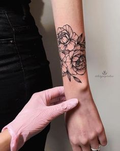 a woman is getting her arm tattooed with flowers on the left side of her arm