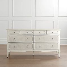 a white dresser sitting on top of a hard wood floor in front of a wall