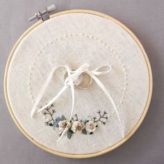 a close up of a embroidery on a piece of cloth with white ribbon and flowers