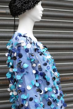 a mannequin wearing a blue dress and hat with buttons on it's head