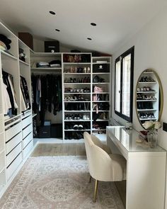 a walk in closet with white shelving and lots of shoes