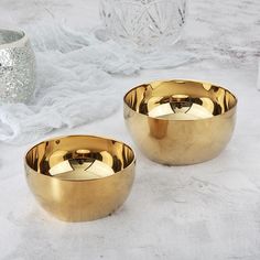 two golden bowls sitting on top of a white table