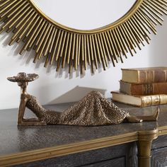 a statue sitting on top of a wooden table next to a mirror and some books