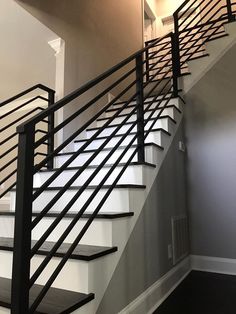 a staircase with black railing and white walls