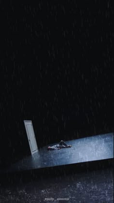 a person laying on top of a floor in the rain next to an open door