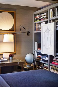 a bed sitting next to a desk with a lamp on top of it in a bedroom