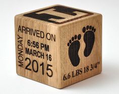 a wooden cube with a baby's footprints and date printed on the front side