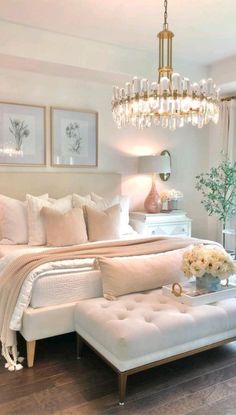 a bedroom with white furniture and chandelier hanging from it's ceiling, along with pictures on the wall