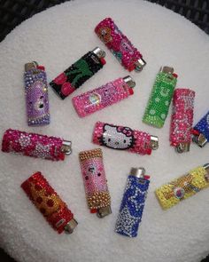 hello kitty lighters are sitting on top of a white cake covered in beads and swaroons