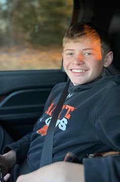 a young man sitting in the back seat of a car