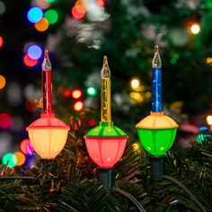 three christmas lights are hanging from a tree with multi - colored lights in the background