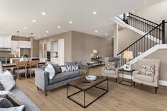 a living room filled with furniture and a stair case in front of a kitchen area