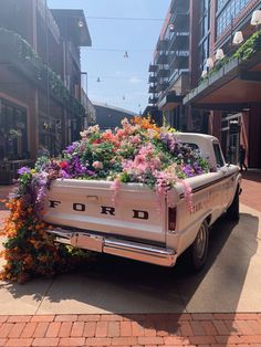 an old pickup truck with flowers in the back